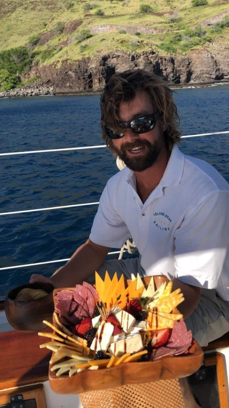 A man is sitting on a boat holding a tray of food.