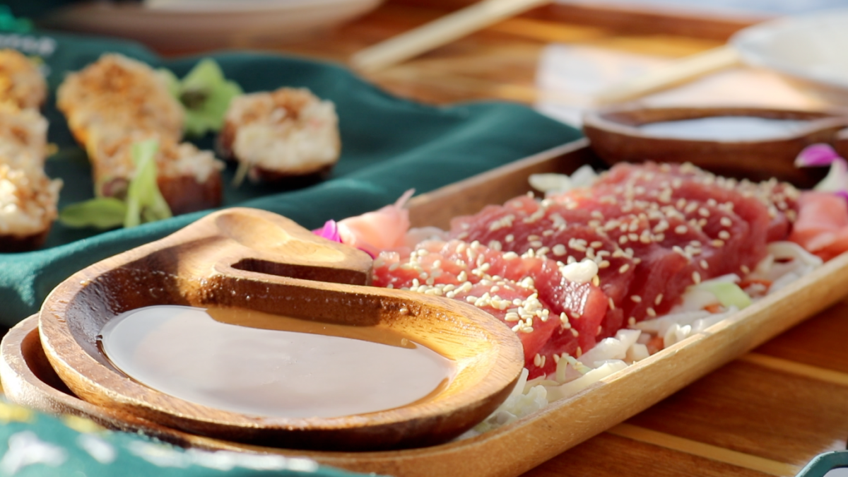 A wooden spoon is sitting on top of a wooden plate of food.
