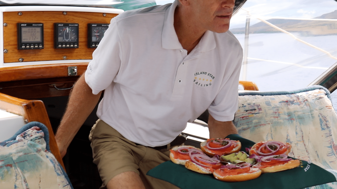 A man sitting on a boat holding a tray of food