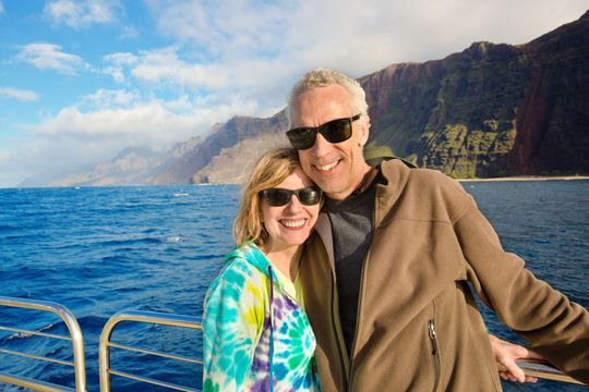 A man and a woman are posing for a picture on a boat in the ocean.