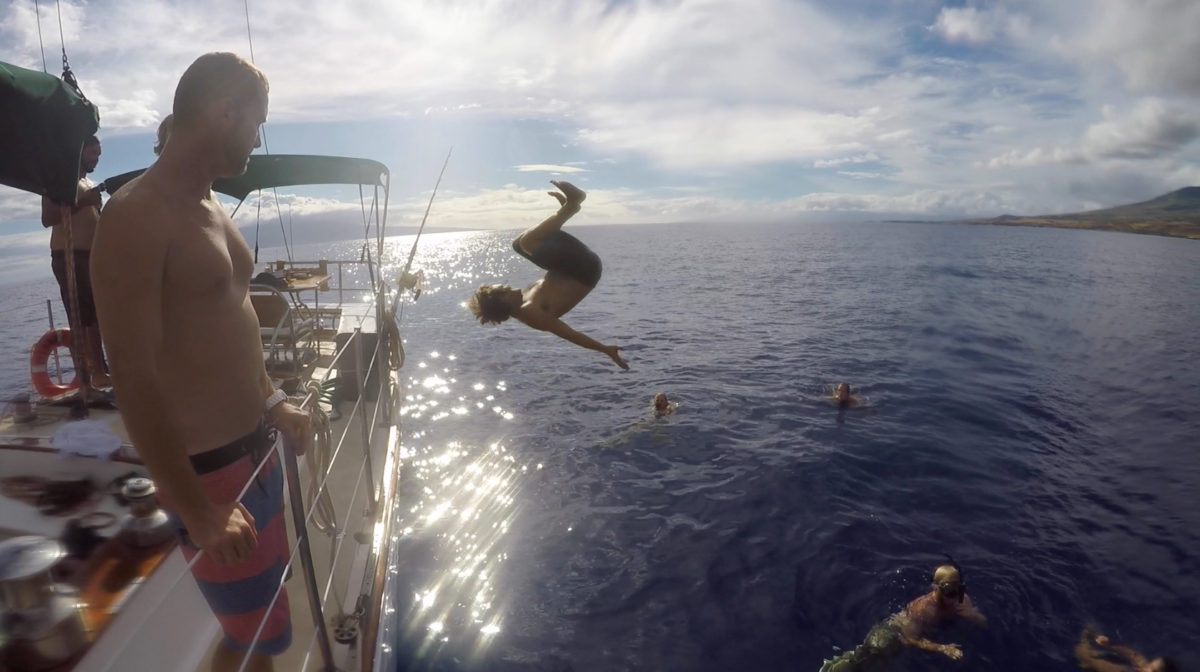 A man is jumping into the ocean from a boat