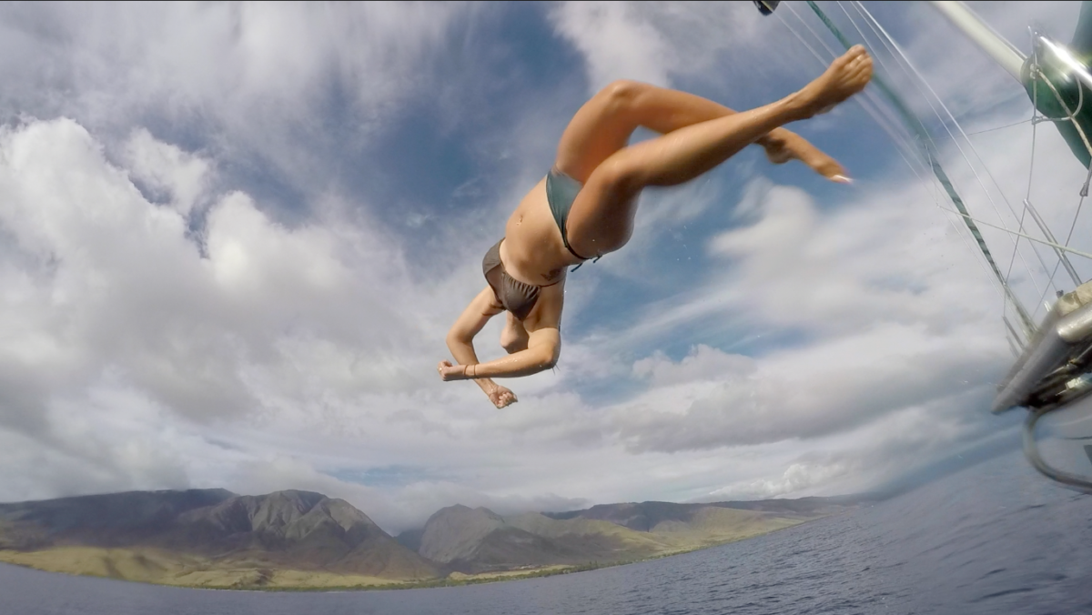 A woman in a bikini is jumping off a boat into the ocean.