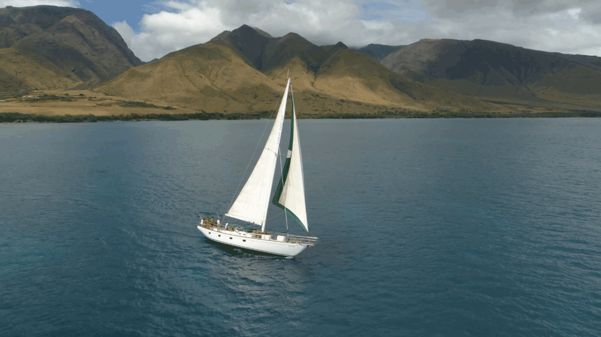A sailboat is floating on top of a body of water with mountains in the background.