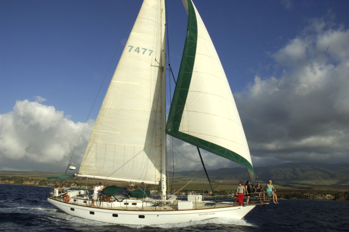 A group of people are sitting on the deck of a boat looking at the ocean.