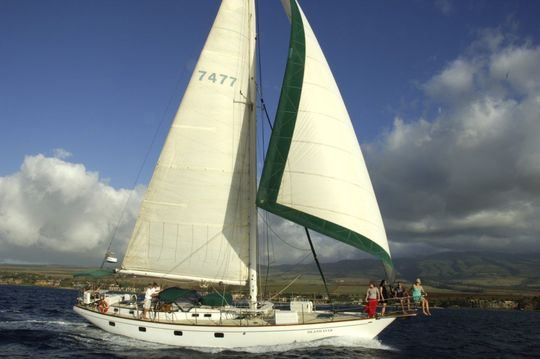 A group of people are sitting on the deck of a boat looking at the ocean.