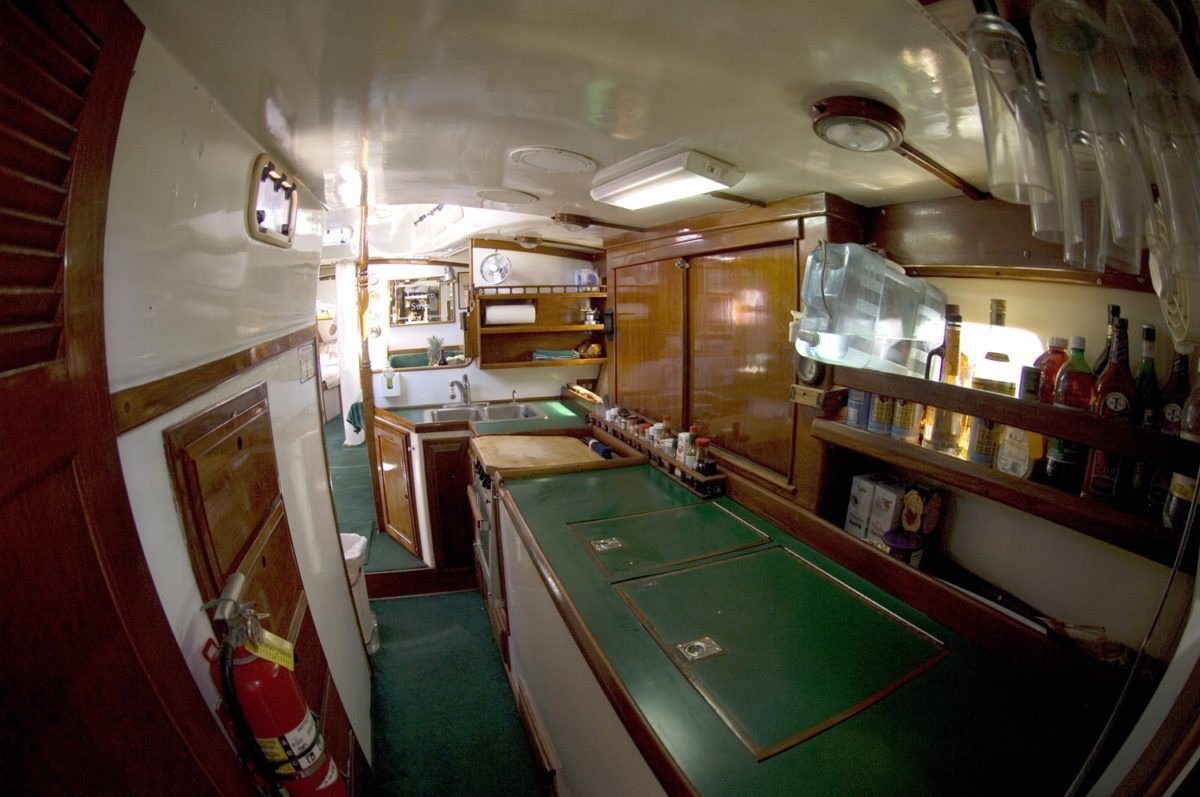 A kitchen on a boat with a green counter top and a fire extinguisher.