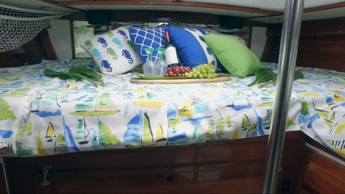 A bed with pillows and a tray of grapes on it on a boat.