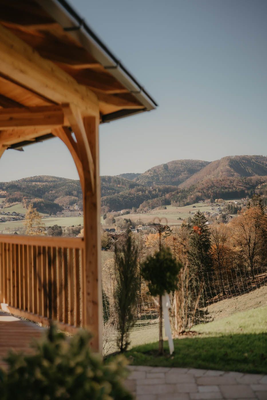 Ein hölzerner Pavillon mit Blick auf ein malerisches Tal mit sanften Hügeln und Bäumen an einem sonnigen Tag.