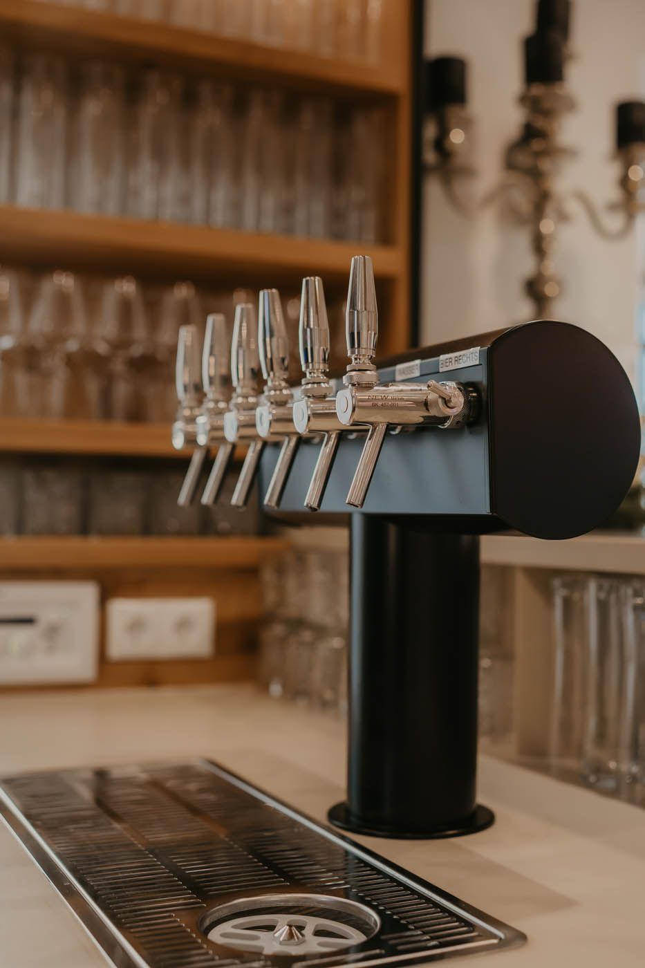 Schwarze Bierzapfanlage an einer Bar. Im Hintergrund sind Regale mit Gläsern zu sehen.