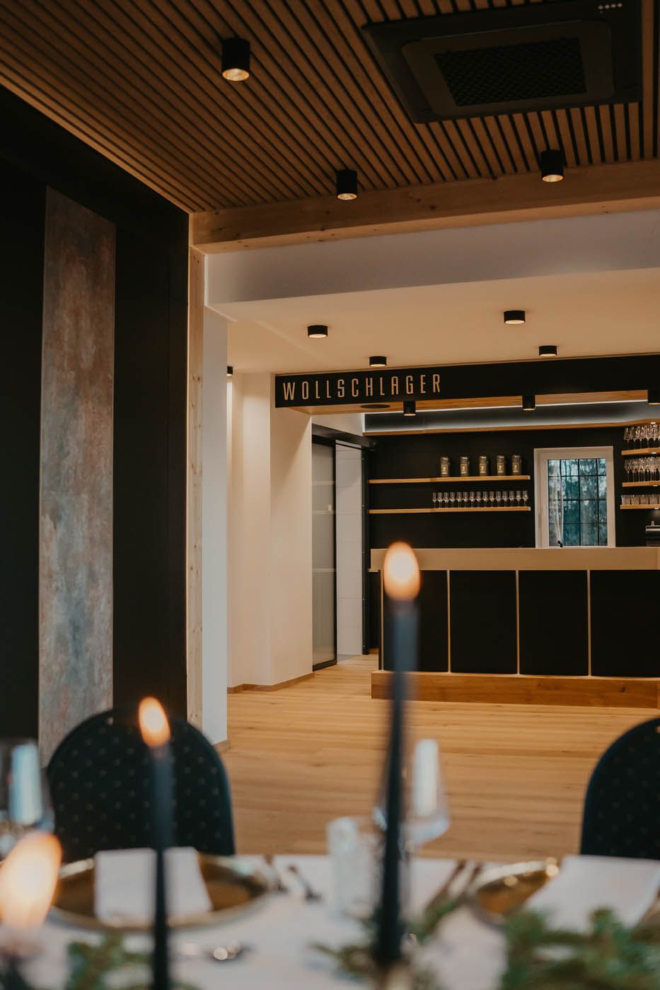 Elegantes Esszimmer mit einem bei Kerzenschein gedeckten Tisch vor einer Bar.