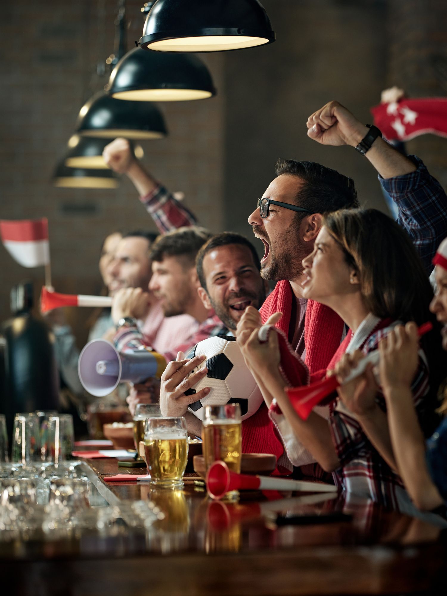 A group of people are sitting at a bar watching a soccer game.