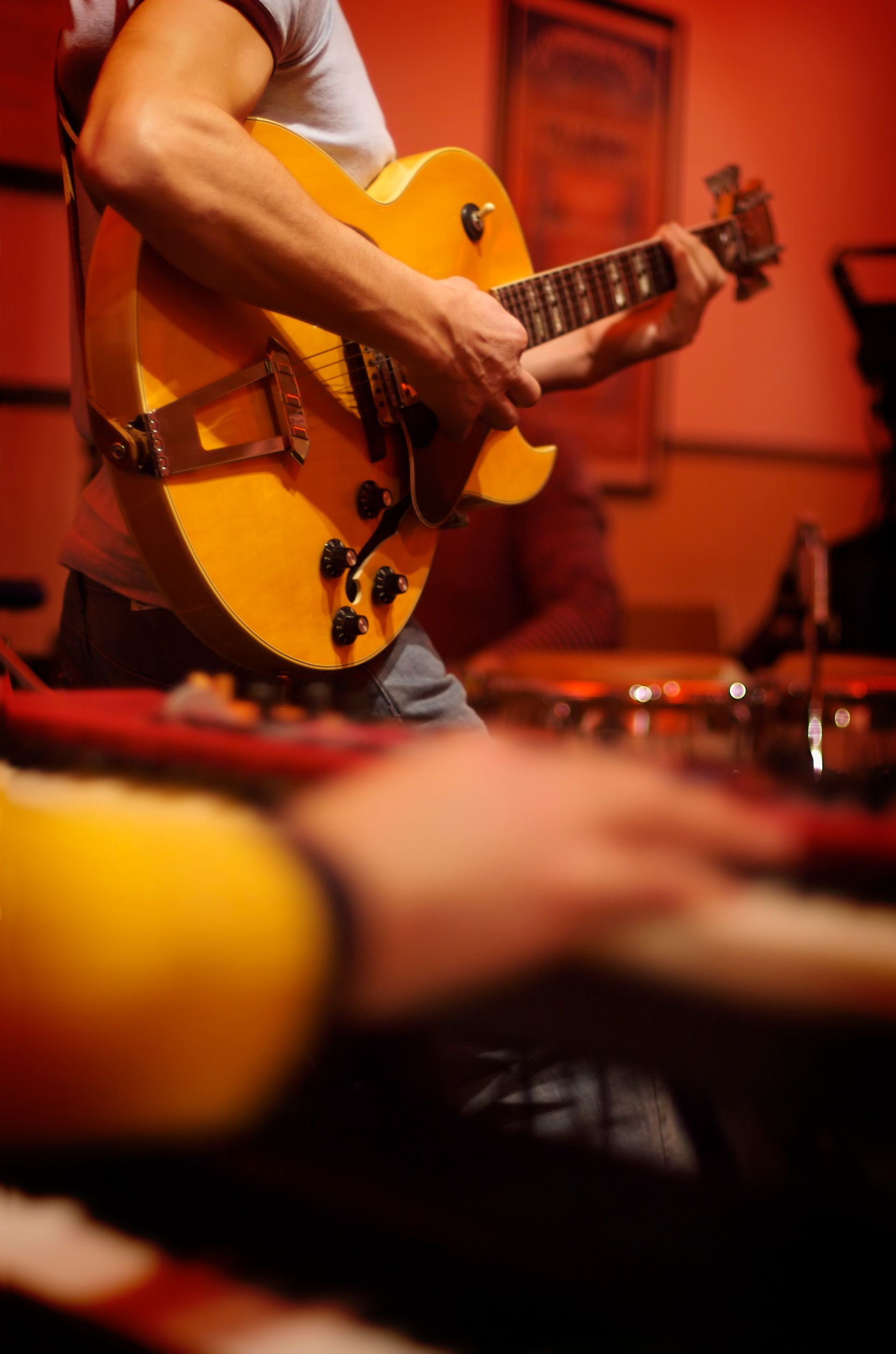 A man is playing a guitar in front of a drum set.