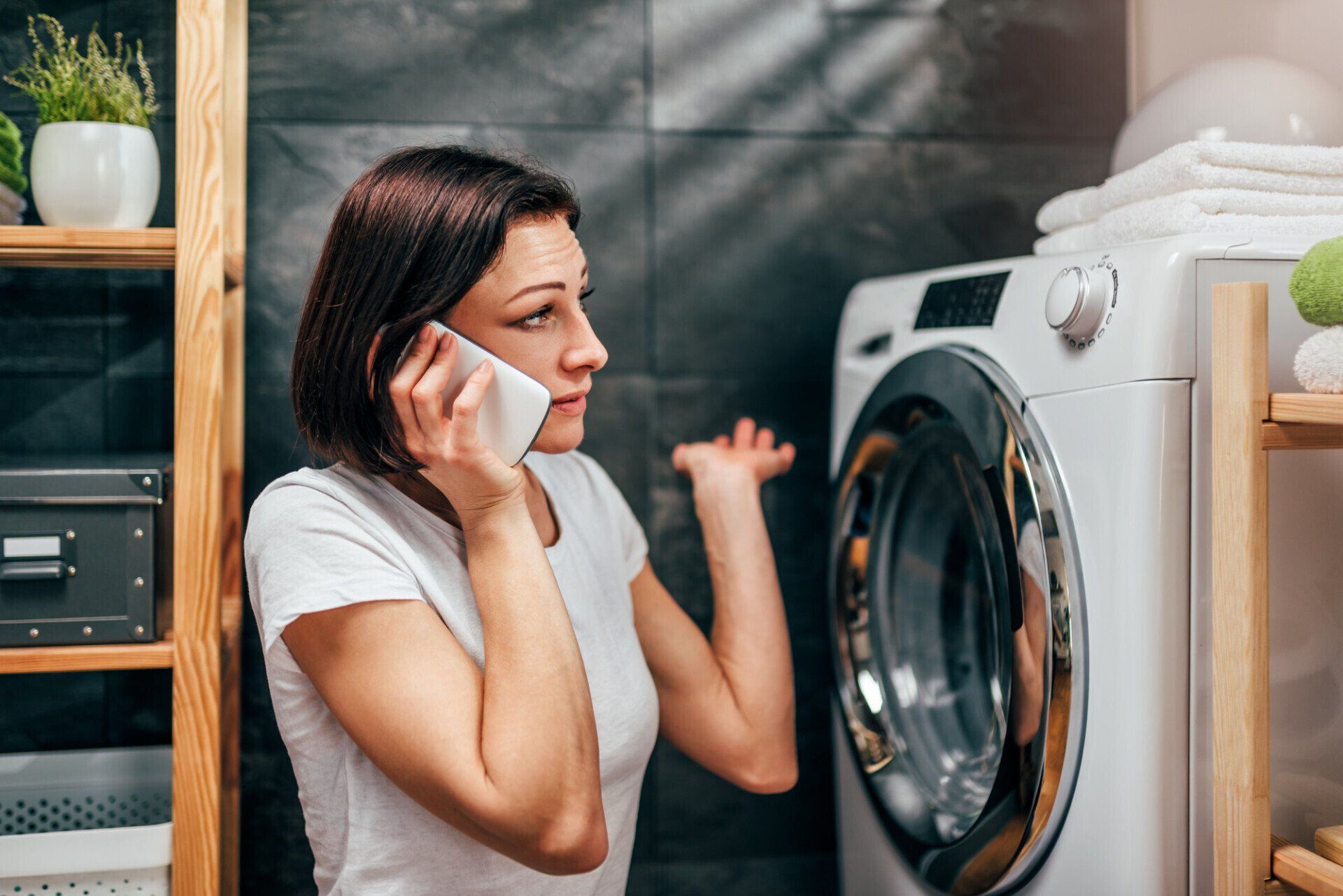 a woman is talking on a cell phone in front of a washing machine .