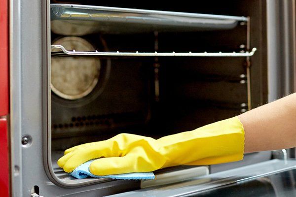 a person wearing yellow gloves is cleaning an oven with a cloth .