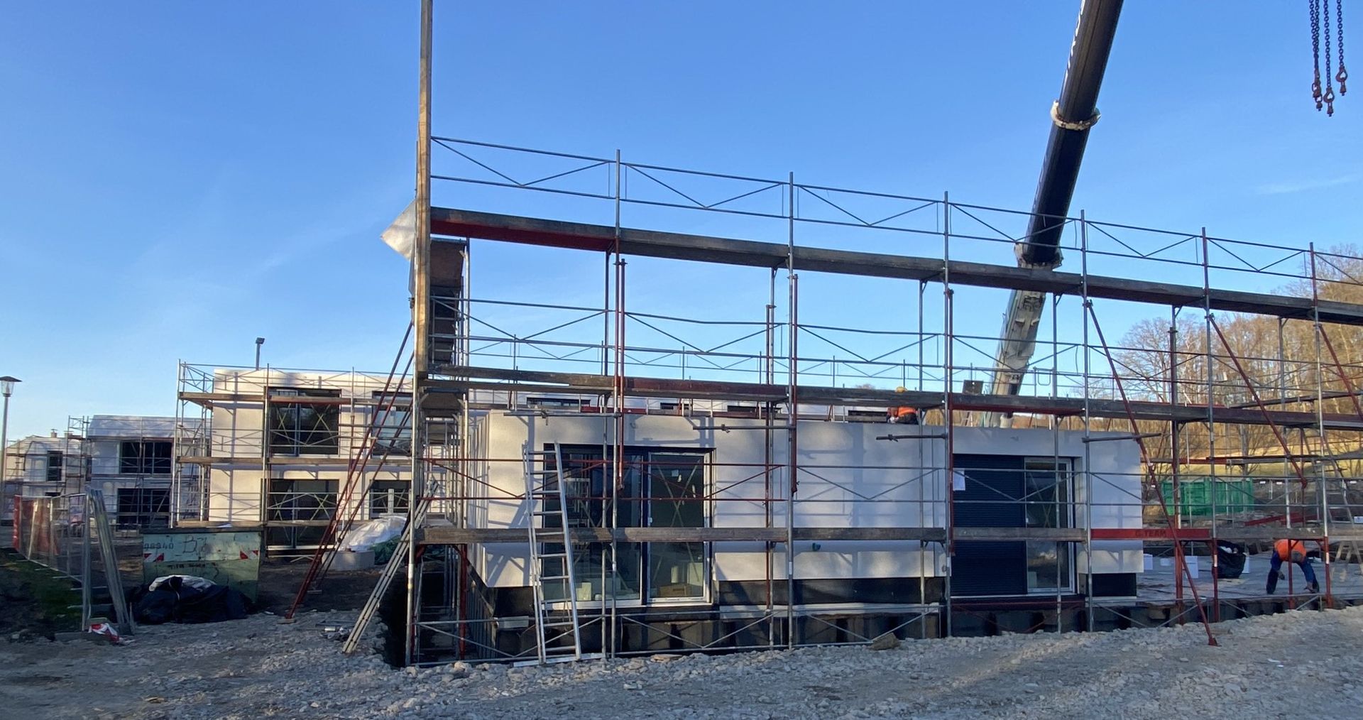 Baustelle mit Gerüsten um ein helles Gebäude unter einem klaren blauen Himmel.