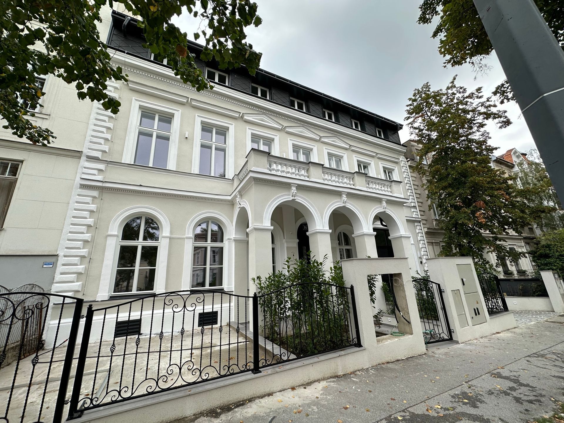 Elegantes dreistöckiges weißes Gebäude mit kunstvollen Verzierungen und Bogenfenstern.