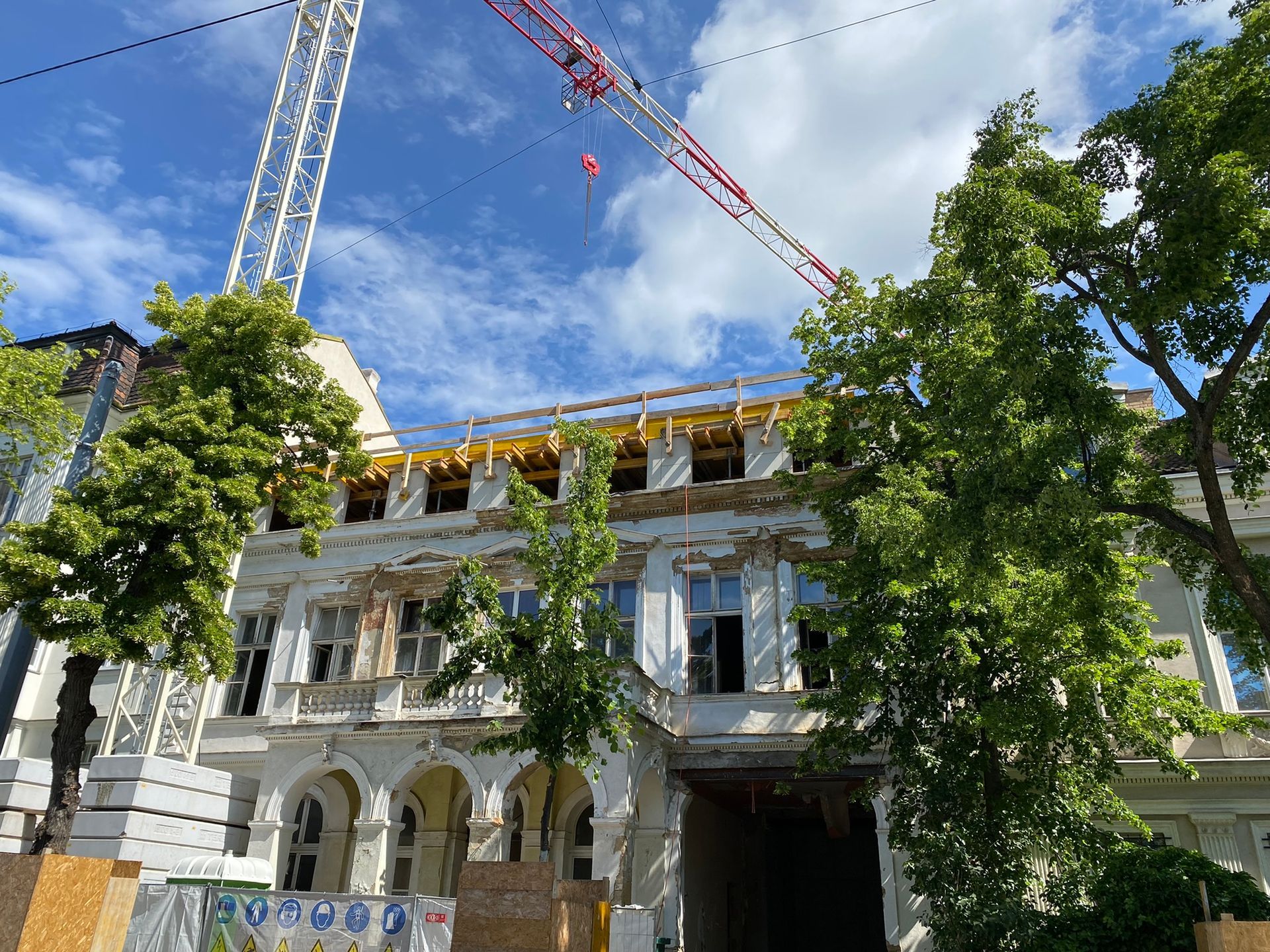 Gebäude wird renoviert, mit Gerüst, Kran und freiliegender Architektur.