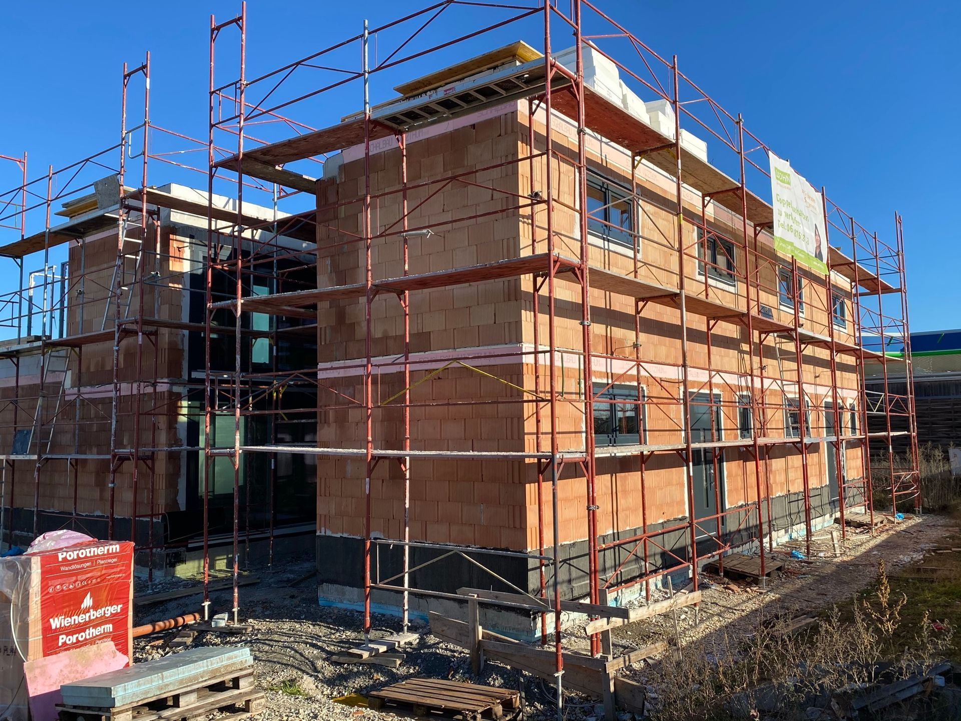 Ein Backsteingebäude im Bau mit Gerüst. Fenster sind sichtbar. Ein klarer, sonniger Tag.