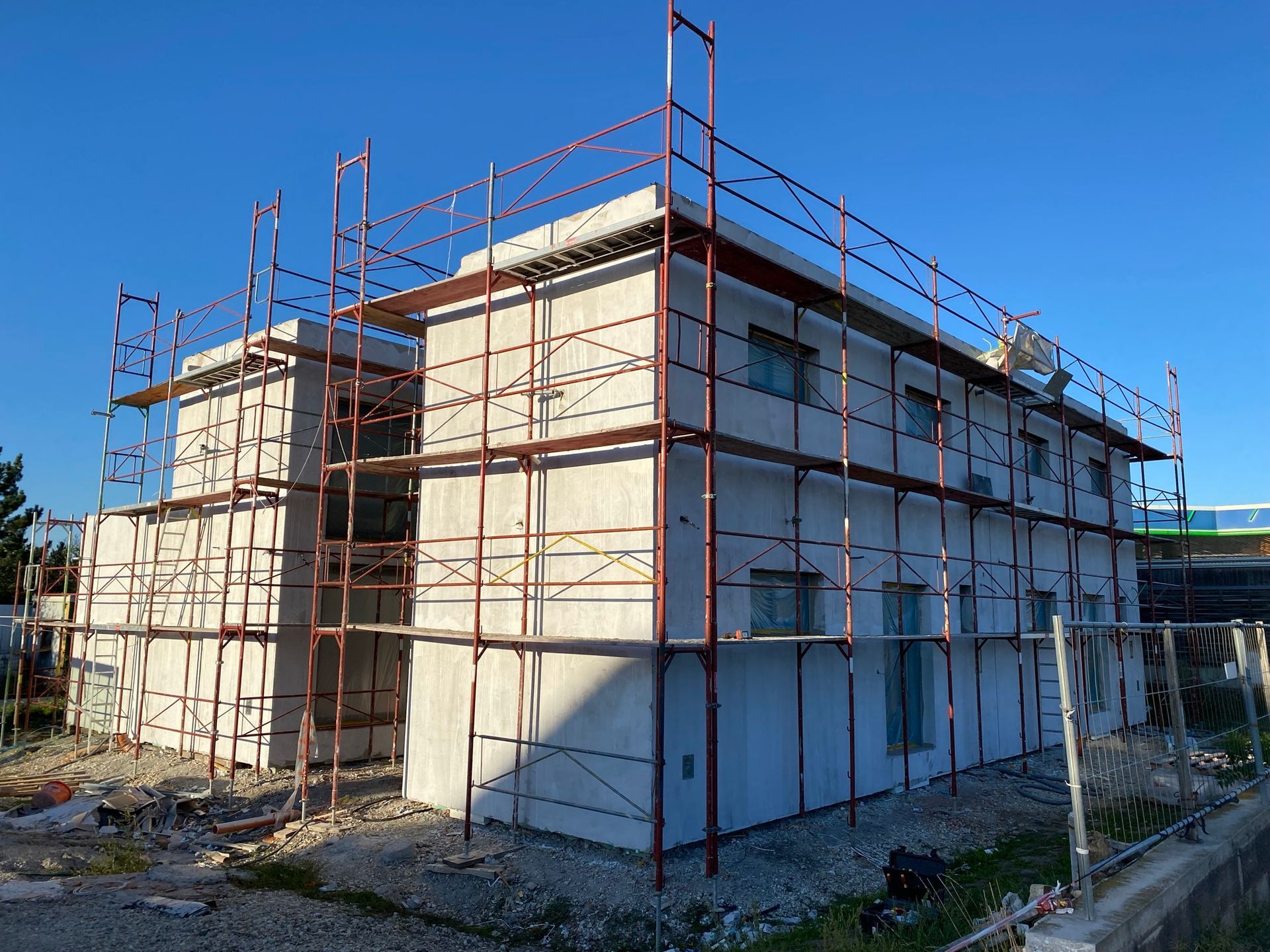 Gebäude im Bau mit Gerüst, grauen Wänden, blauem Himmel.