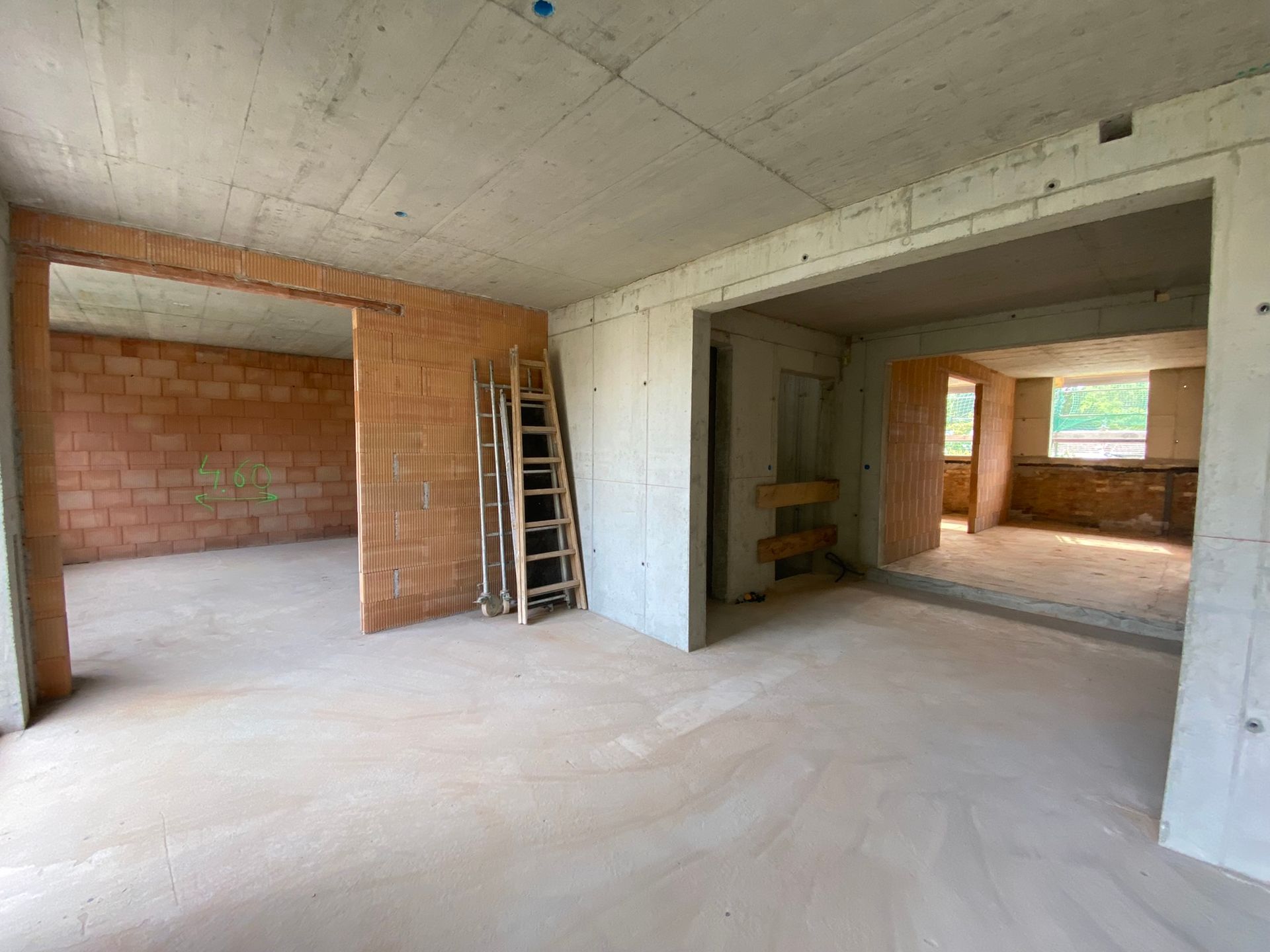Innenansicht eines im Bau befindlichen Gebäudes mit unverputzten Ziegel- und Betonwänden.