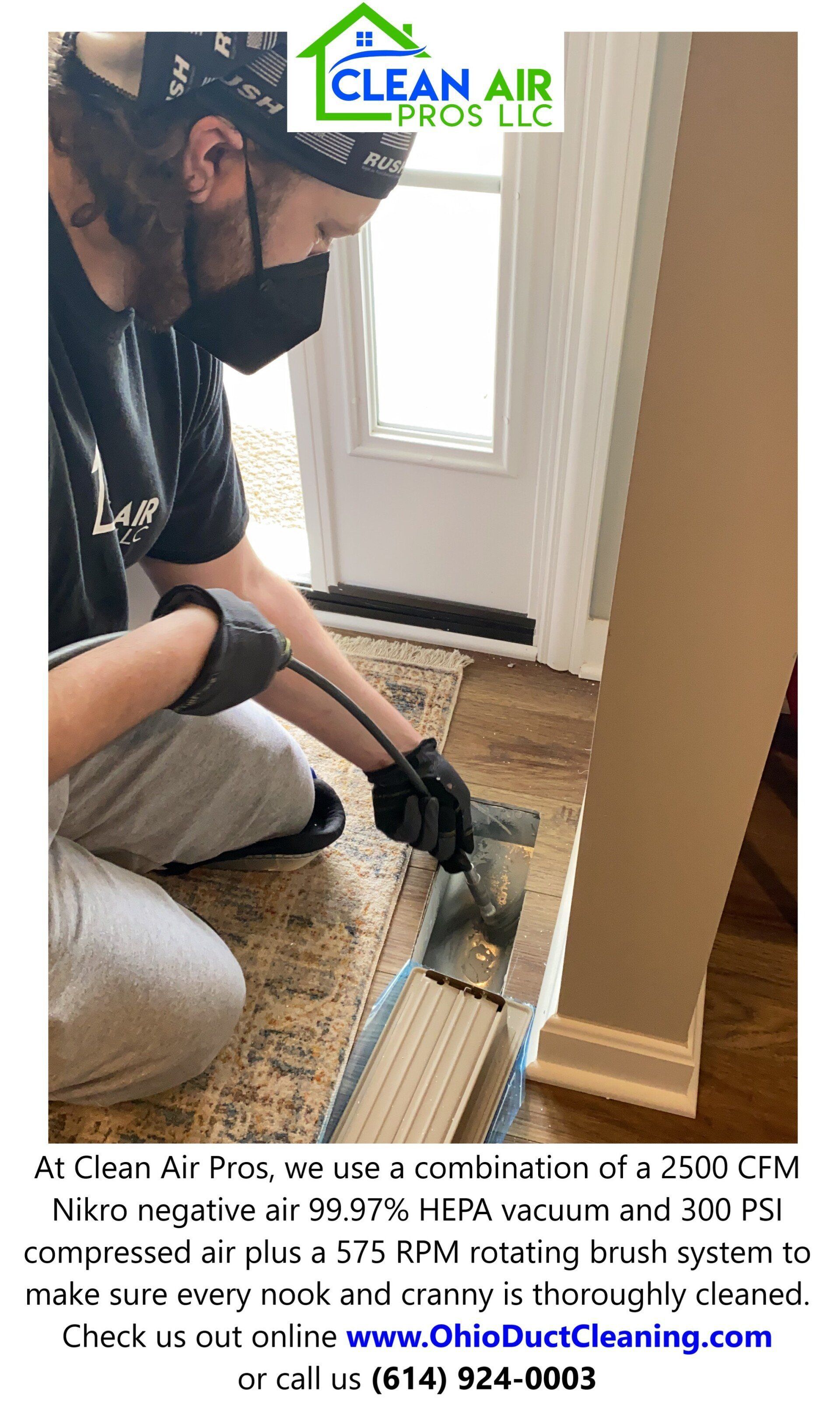 Person cleaning a floor vent with a vacuum.