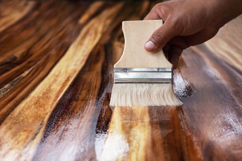 Application manuelle de vernis au pinceau sur une table en bois