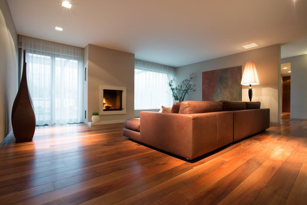 Salon moderne avec canapé d'angle marron, cheminée, parquet et fenêtres allant du sol au plafond