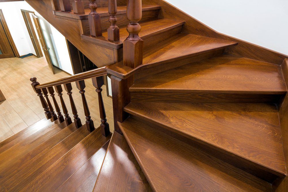 Escalier en colimaçon en bois avec rampe sculptée dans un couloir intérieur lumineux