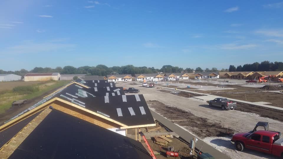 A red truck is parked in front of a building under construction.