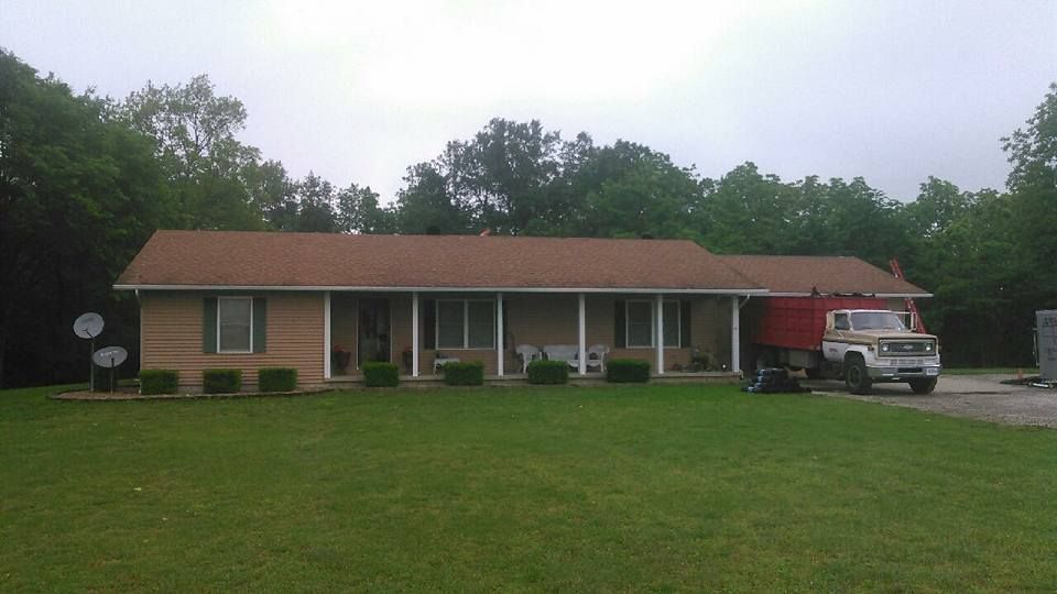 A red truck is parked in front of a brick house.