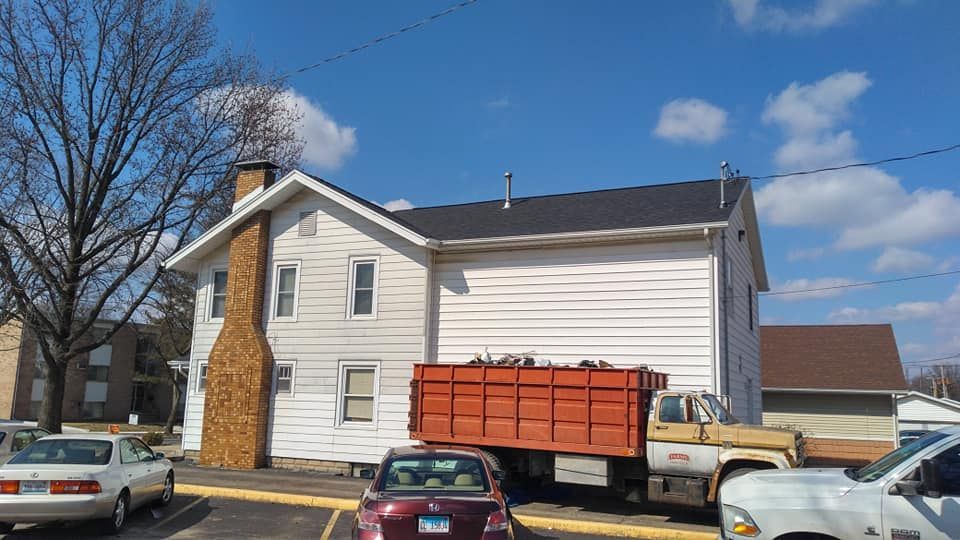 A red dump truck is parked in front of a white house.