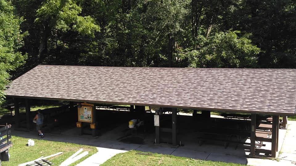 A picnic shelter in the middle of a park with trees in the background
