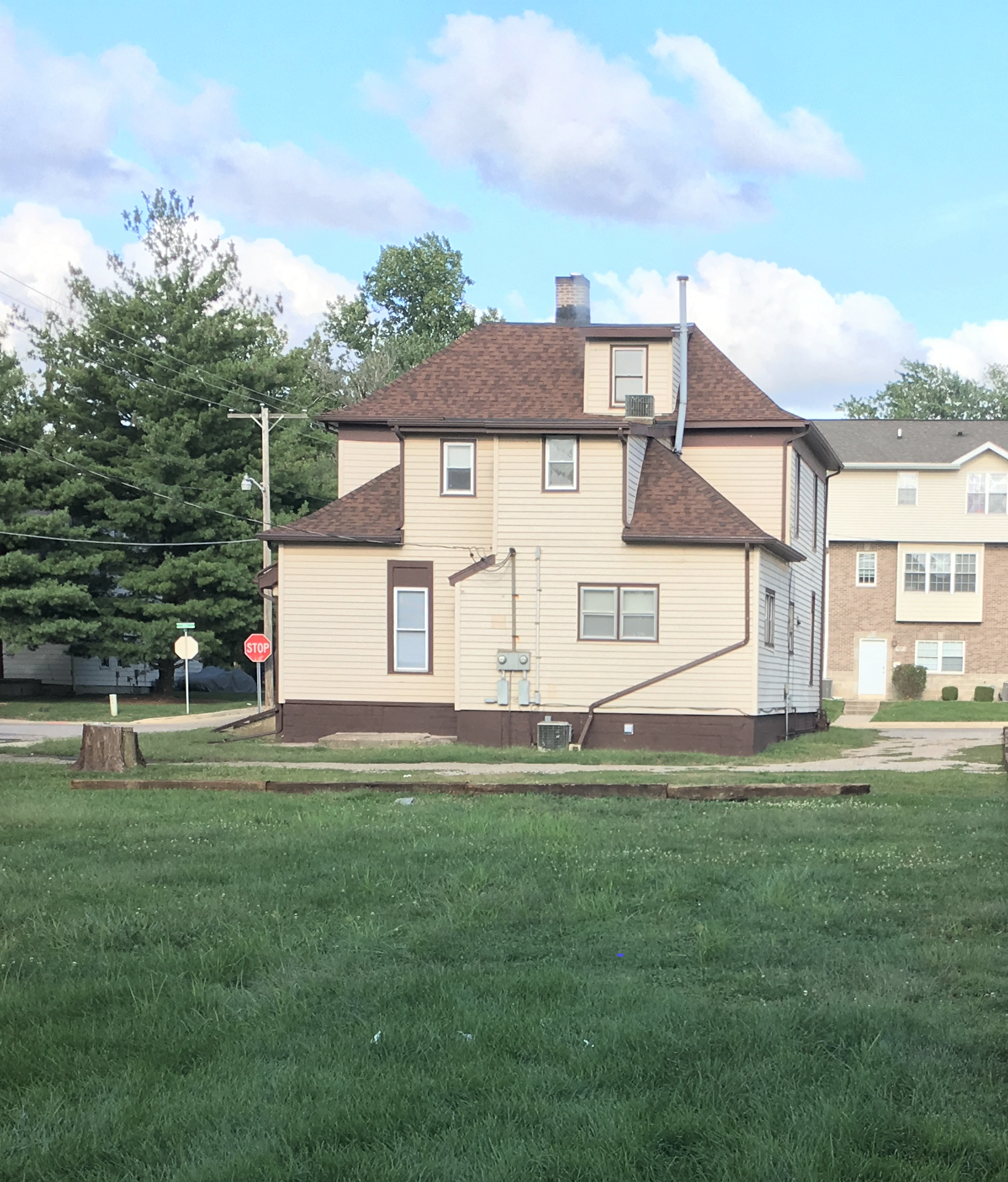 A house with a brown roof sits in the middle of a lush green field