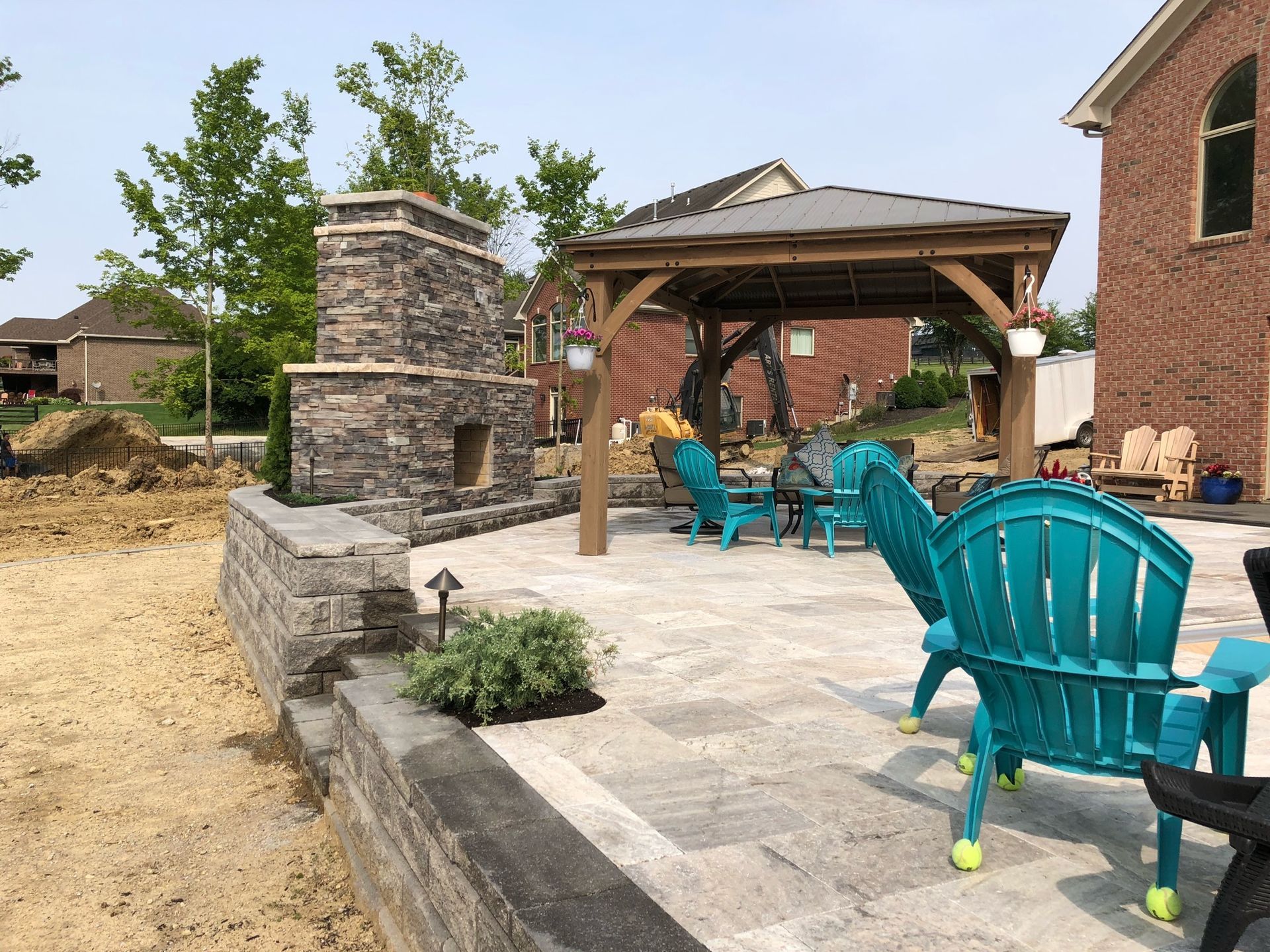 A patio with blue chairs and a fireplace in the background.