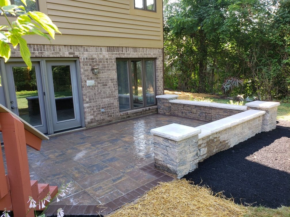 A brick house with a patio and a stone wall in front of it.