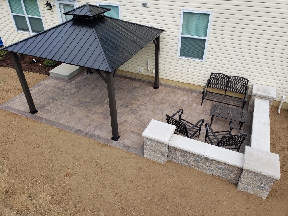 An aerial view of a patio with a gazebo and chairs in front of a house.