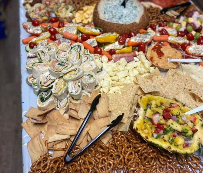 A table topped with a variety of food including pretzels, crackers, and a pineapple.