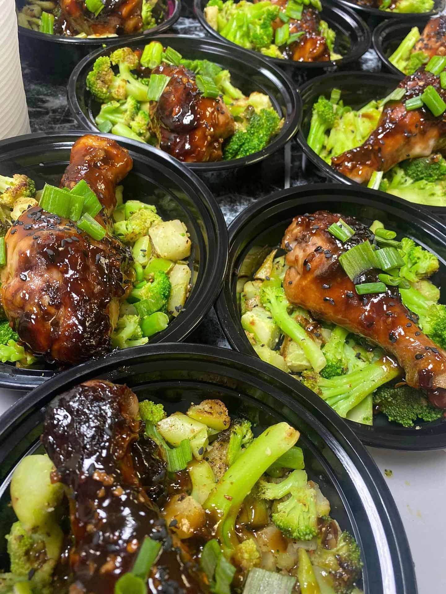 A bunch of bowls of food with broccoli and chicken on a table.