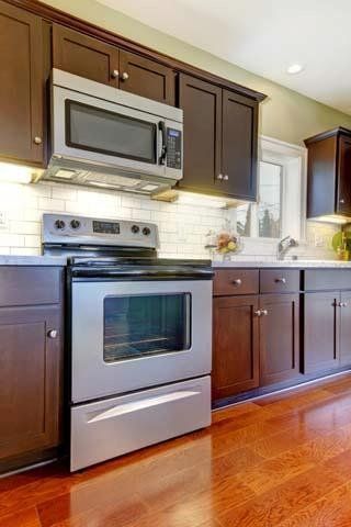 Kitchen with stainless steel oven and microwave, dark brown cabinets, and hardwood floors.