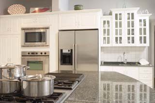 White kitchen with stainless steel appliances, cabinets, and cookware on the stove.