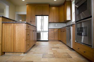 Kitchen with light brown cabinets, stainless steel appliances, and stone-like tile flooring.