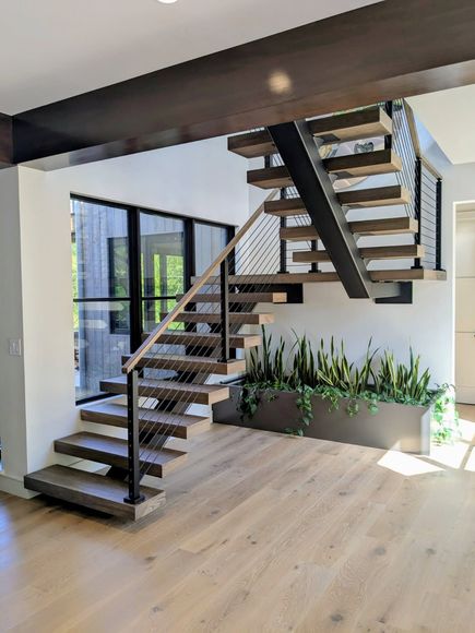Staircase with gray steps and black metal railings, leading upwards. Walls are beige and white.