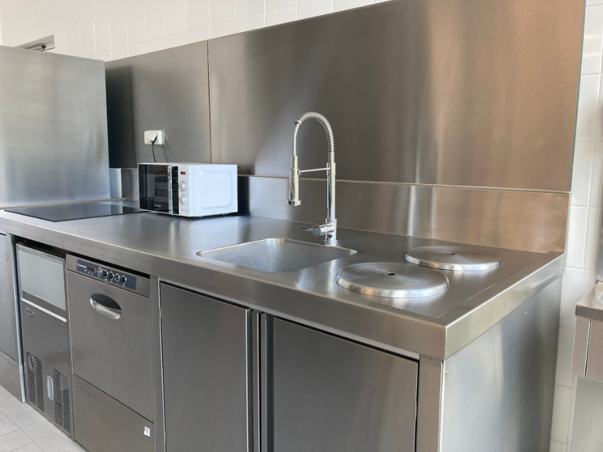 Une cuisine en acier inoxydable avec un évier, une cuisinière, un micro-ondes et un lave-vaisselle.