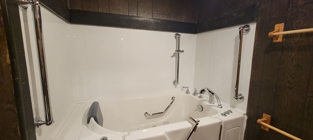 A white walk-in tub with chrome fixtures and grab bars, set in a bathroom with dark wood paneling.