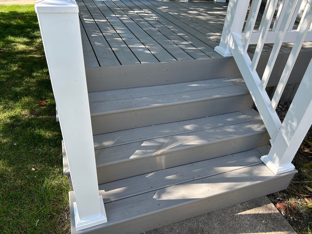 Gray composite deck with white railing and steps, outdoors.