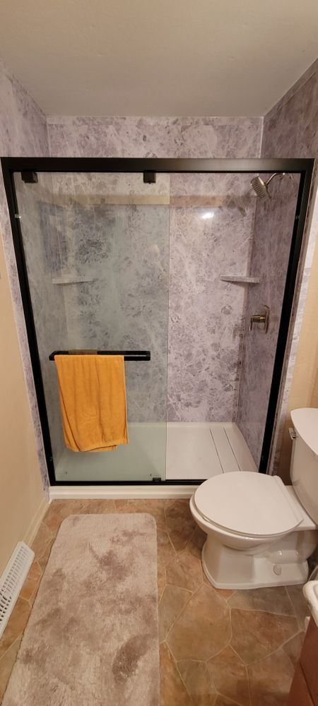 Bathroom with a shower stall, a toilet, and a bath mat.