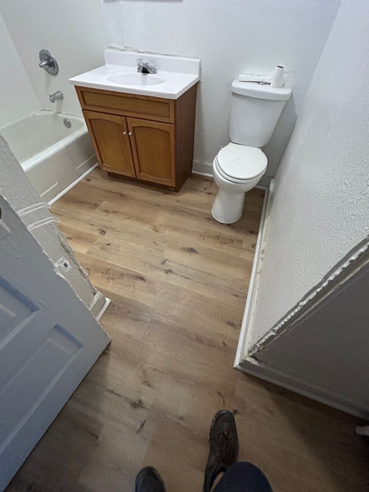 Bathroom with wood-look flooring, a vanity with a sink, a toilet, and a bathtub.