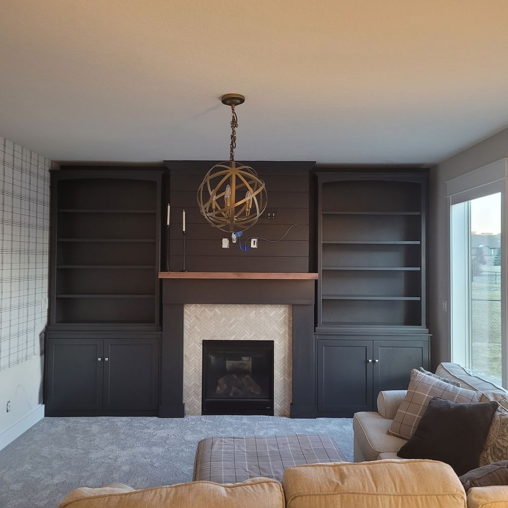 Living room with fireplace and built-in bookshelves, dark grey paint, lit with a gold chandelier.