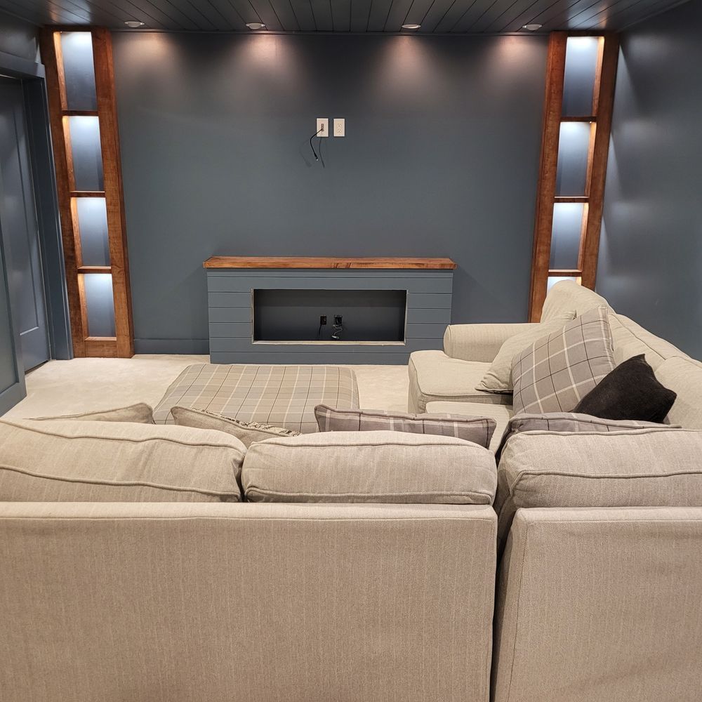 Cozy living room with gray sectional, blue wall, built-in fireplace, and wooden accent lights.