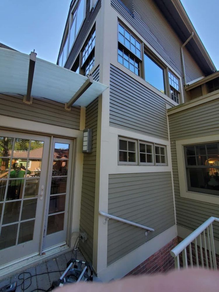 Exterior of a multi-story building with gray siding, windows, and a covered patio.